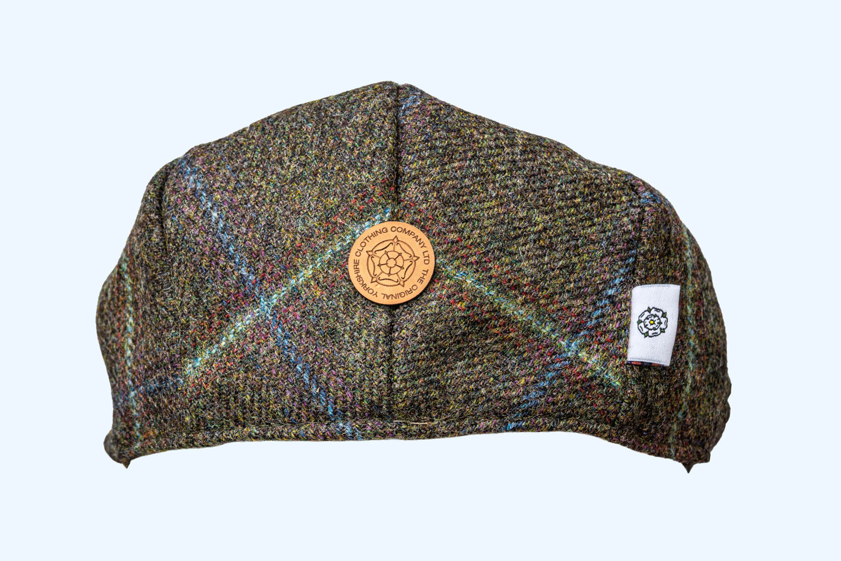 Tweed flat cap with a logo on a light grey background