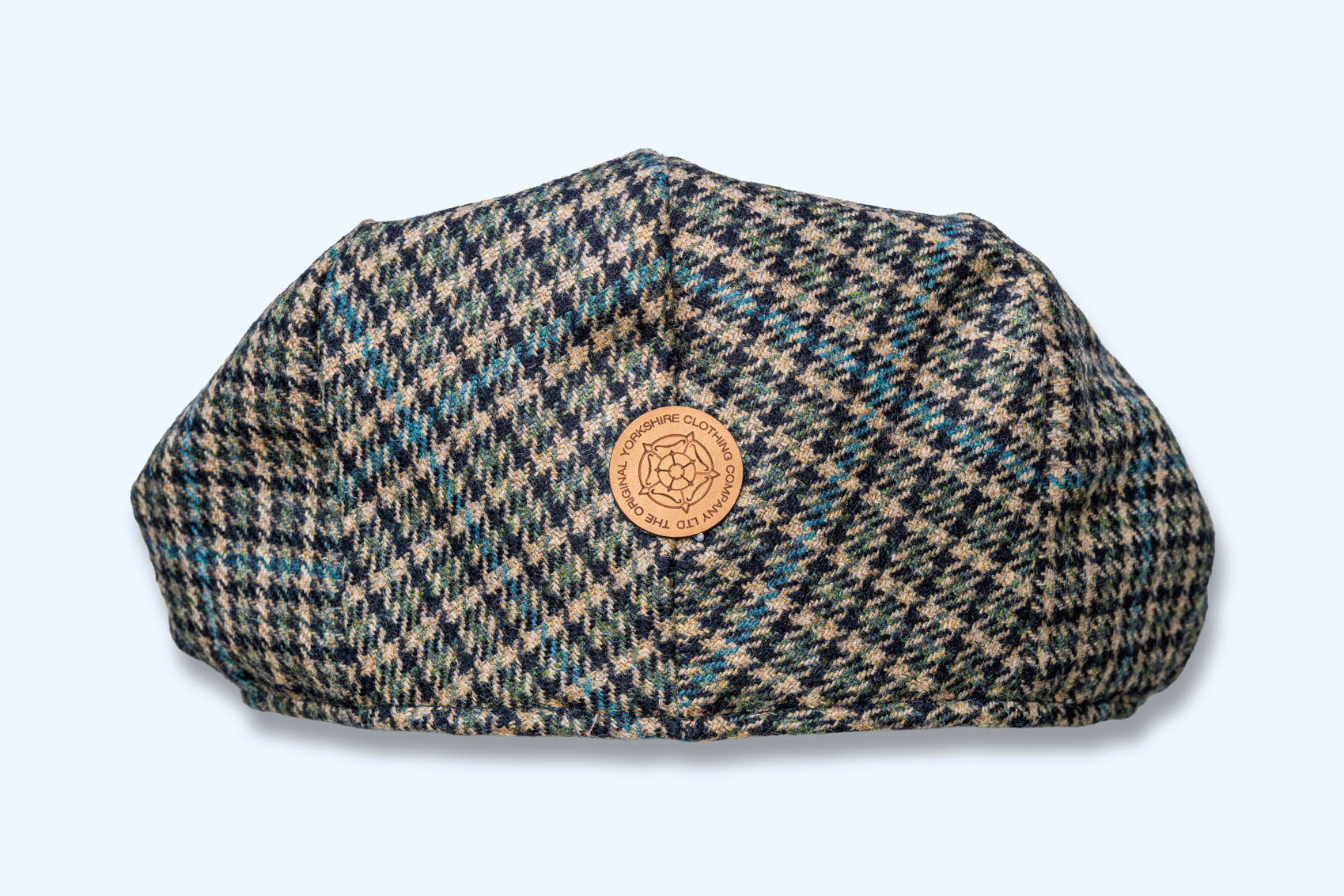 Houndstooth patterned cap with a leather patch on a light background