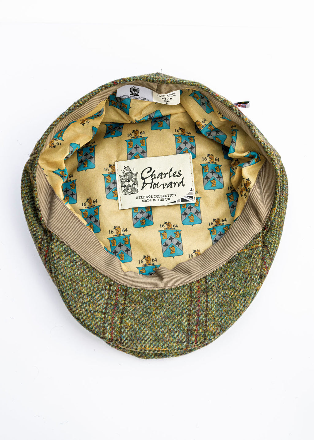 Green tweed flat cap with Yorkshire patterned interior and visible brand label on a white background