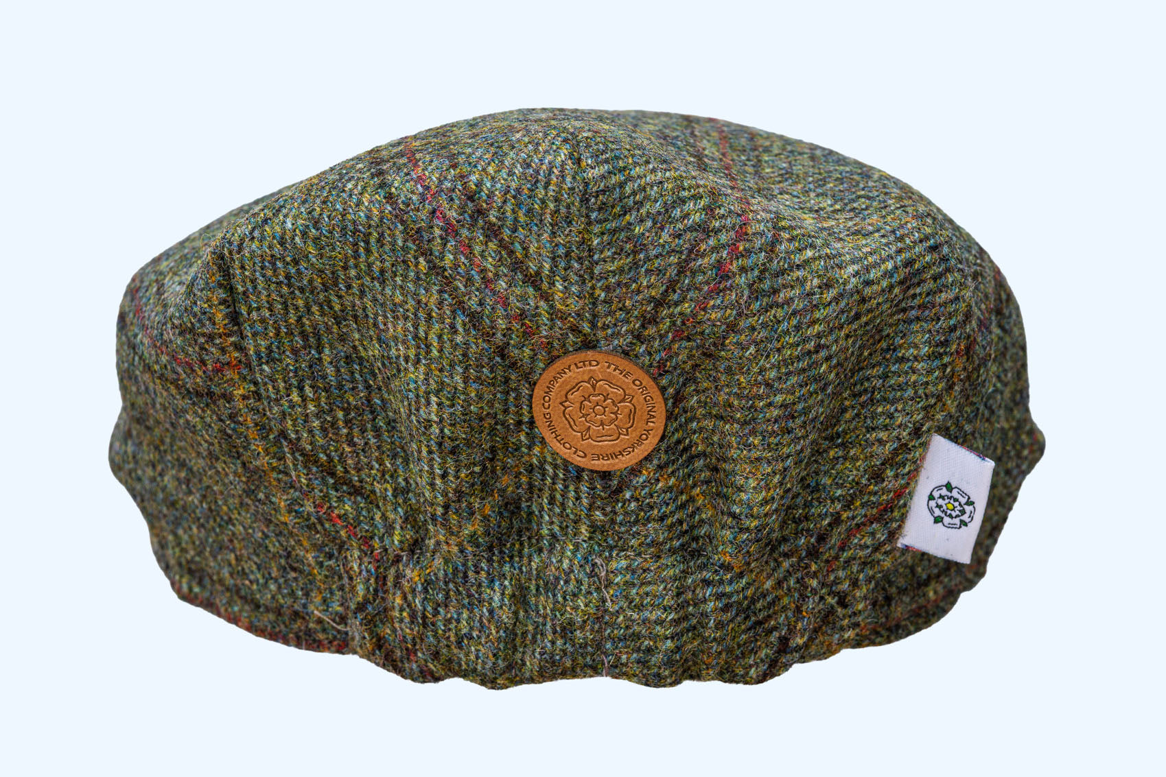 Green tweed cap with a button and label on a white background